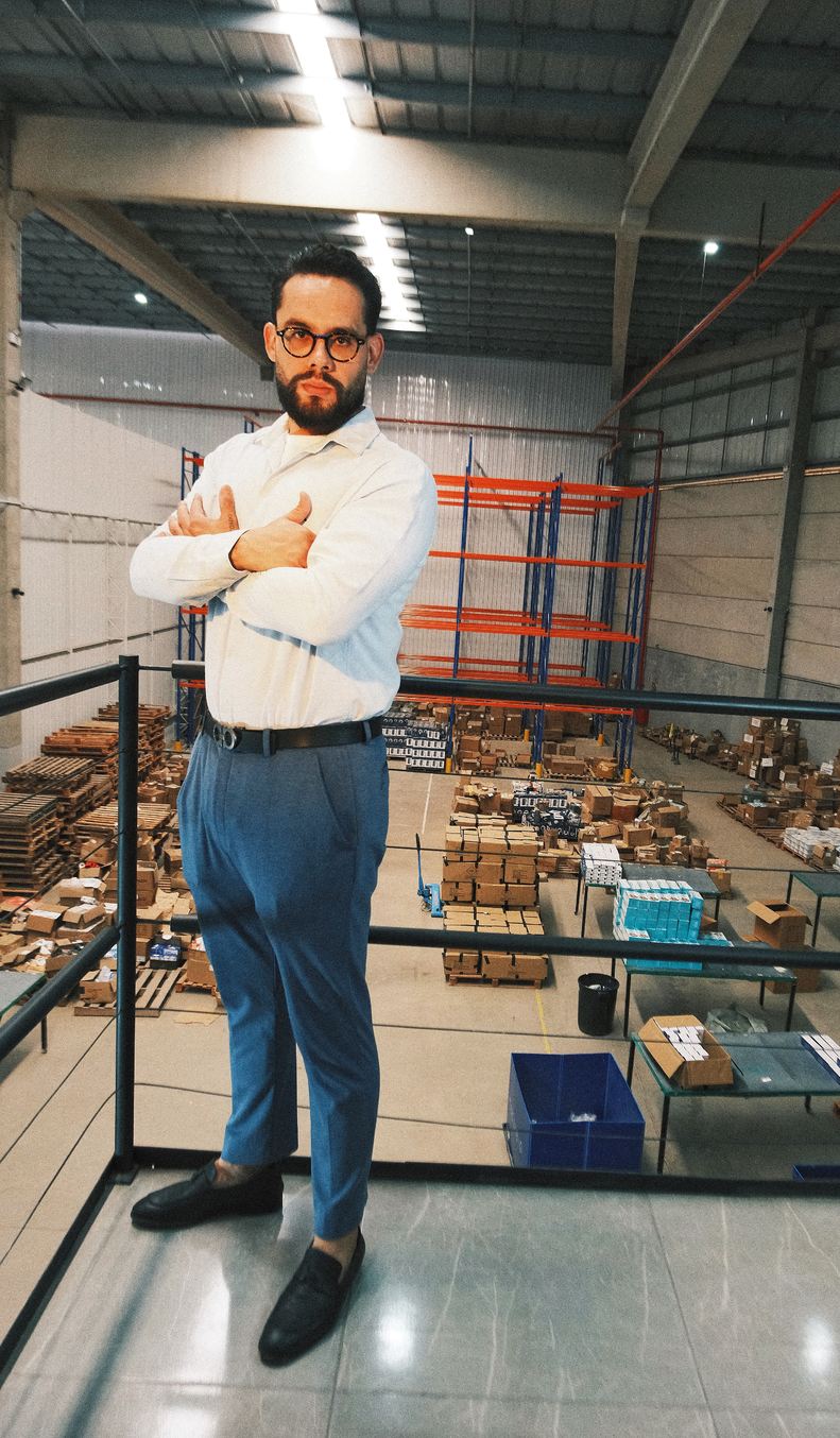 Mateus Preisler dentro do galpão da operação, com os porta-paletes ao fundo